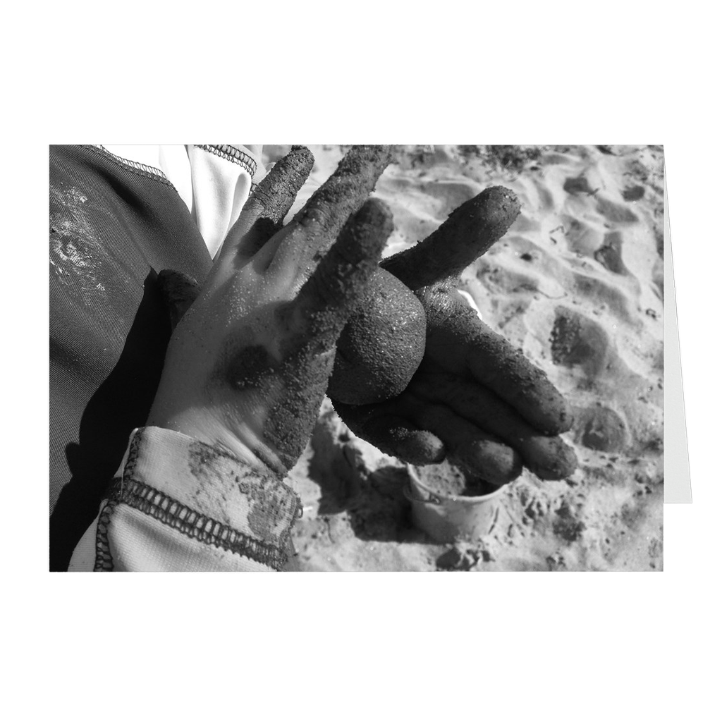Meghan Nathanson Artistry black and white photo of a child's hands holding a ball of sandy mud on folded greeting card